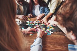 Image of friends playing a board game | Featured image for How to Teach Board Games blog.