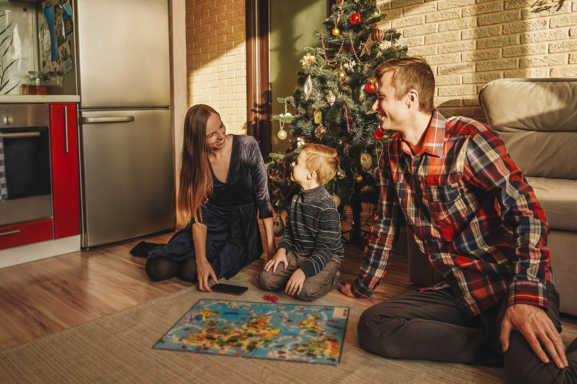 Family playing a board game on Christmas | Featured image for the Best Games for Christmas Parties blog on More Than Meeples.