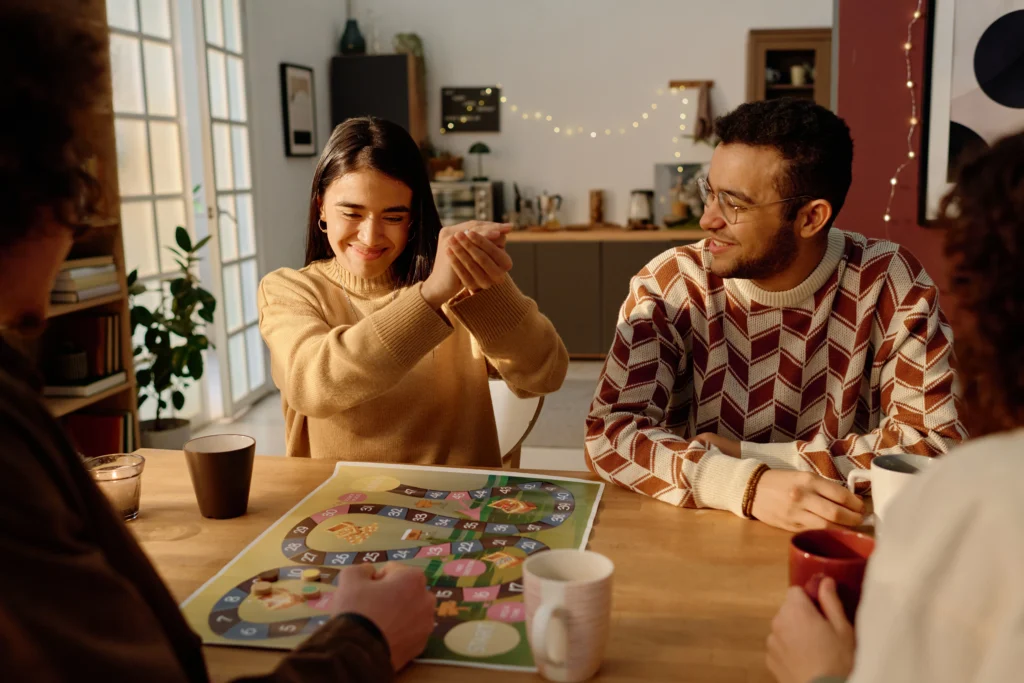 Four people are sitting around a table playing a board game.