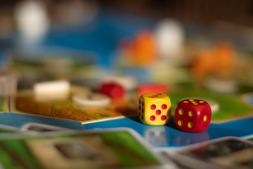 A close up photo of dice next to a game board | Featured image for the Relaxing Strategy Games blog.
