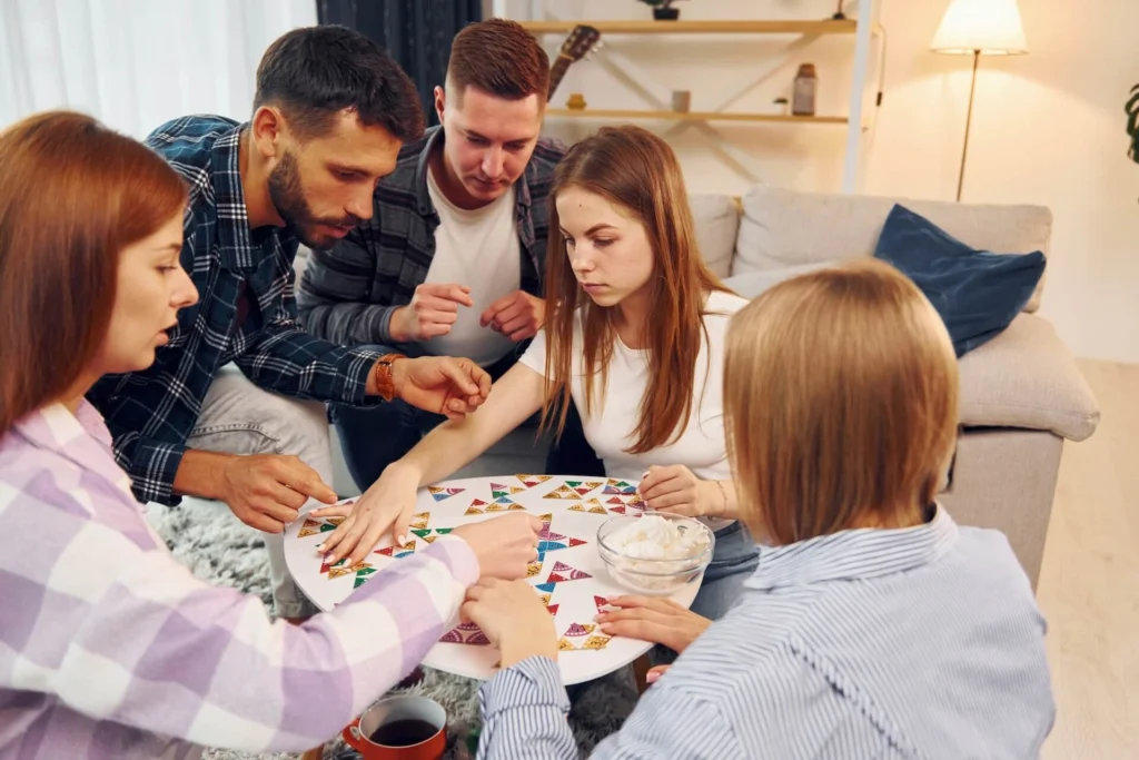 Family playing a board game in their living room | Featured Image for the The Best Party Games for Families blog.